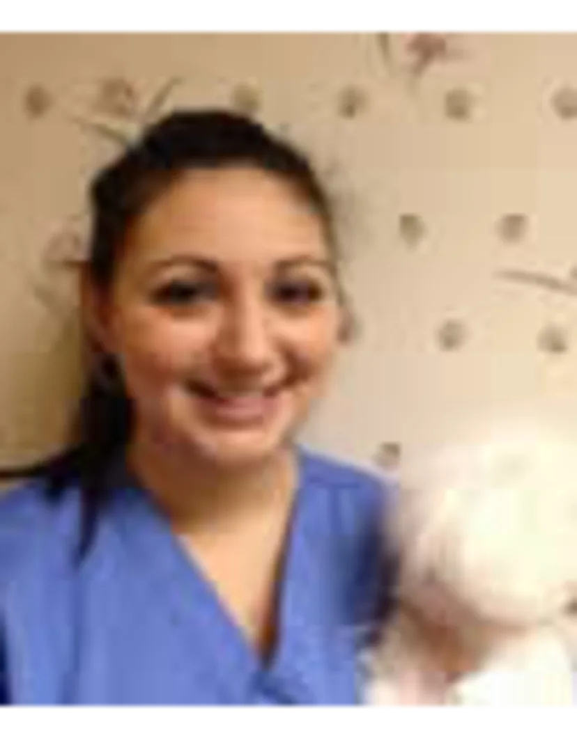 Maria Gatto's staff photo from Shinnecock Animal Hospital where she posing with a white dog in her arms.